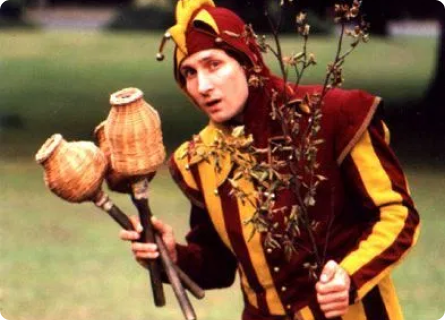 young white male in jester outfit and 3 juggling sticks