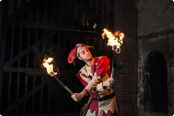 man in jester outfit juggling fire