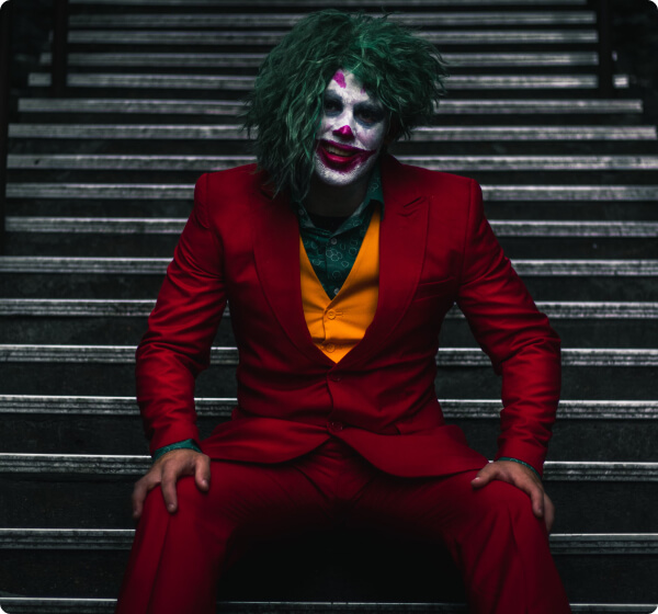 cosplay joker in red suit sitting on stairs