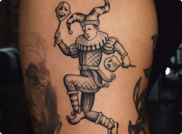 black ink tattoo of a jester on a persons shin