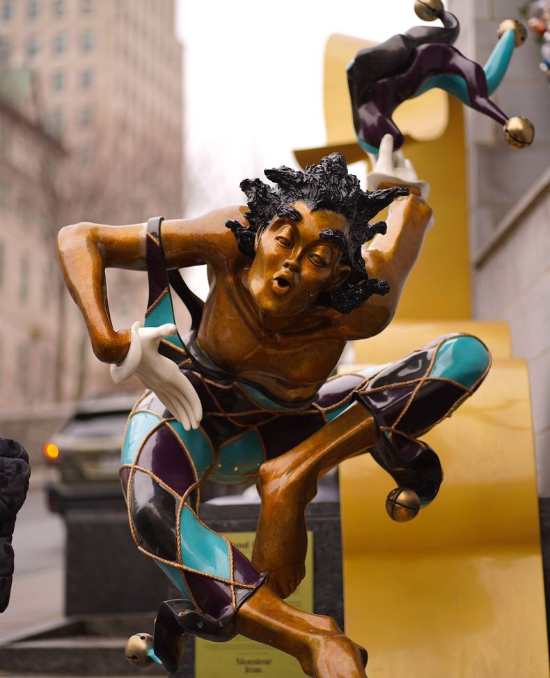 Colorful sculpture of a jester with an expressive pose.