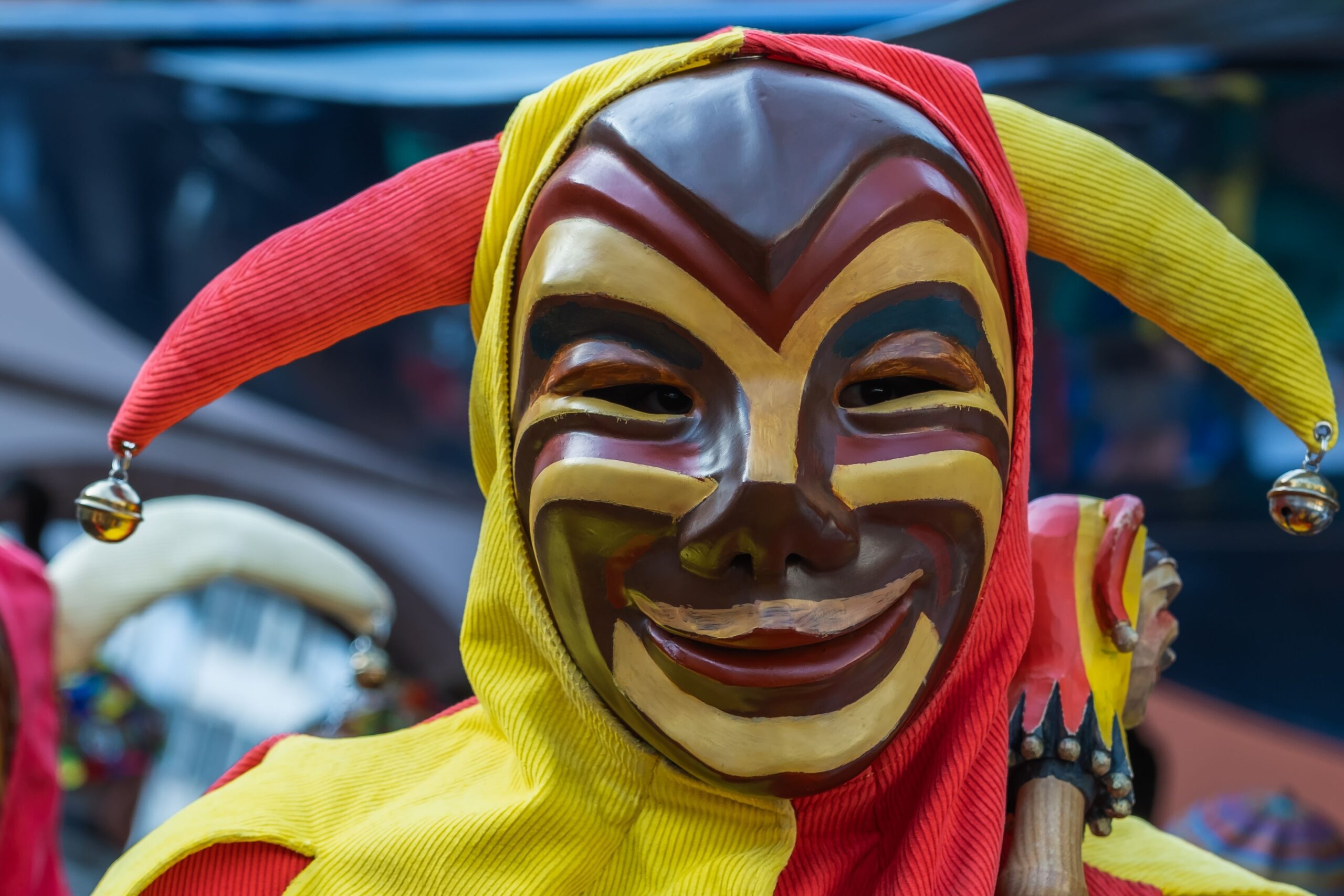 Person in colorful jester costume with a painted mask